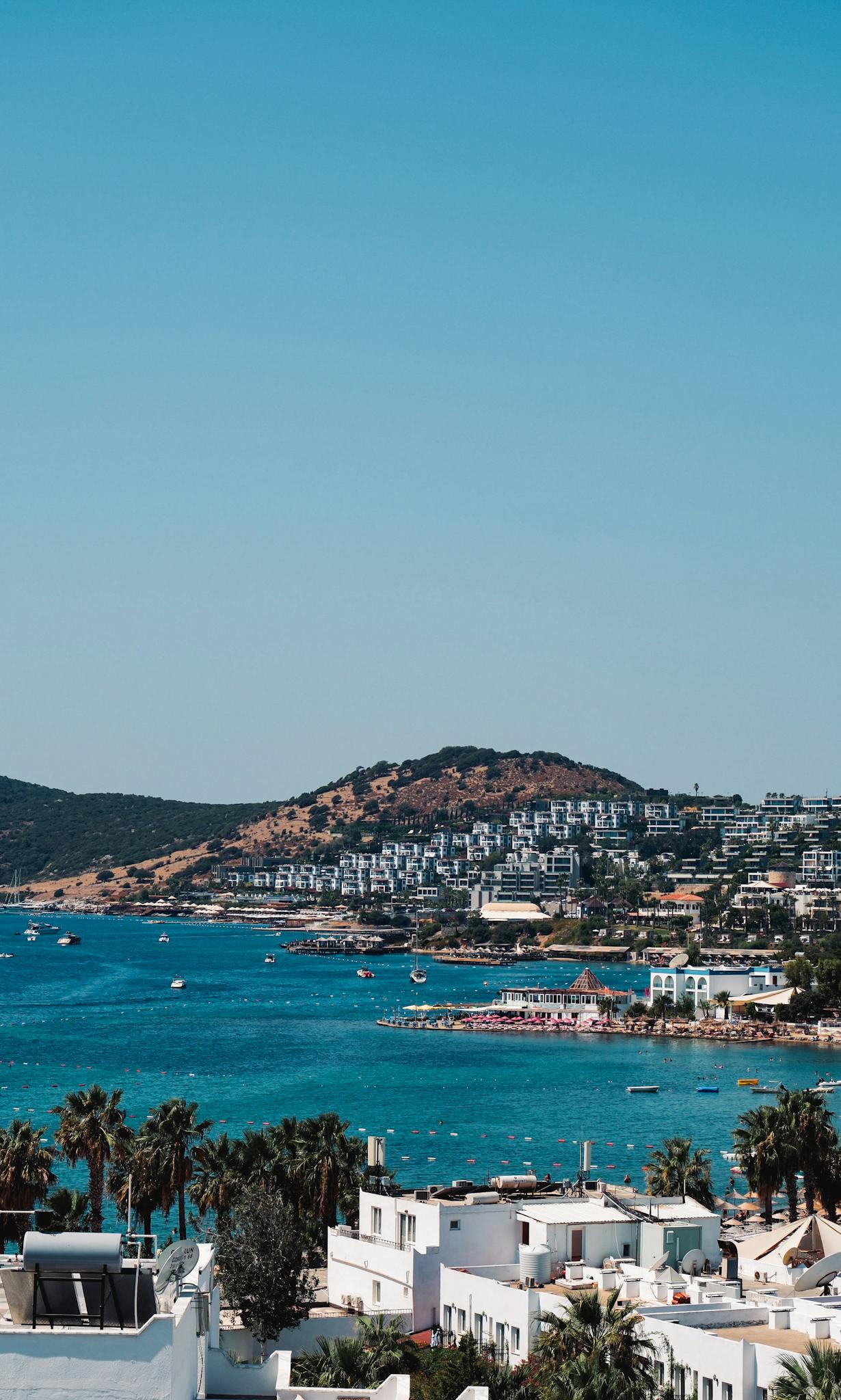 A picturesque view of Bodrum Bay in Türkiye, featuring vibrant blue waters and hillside homes under a clear sky.