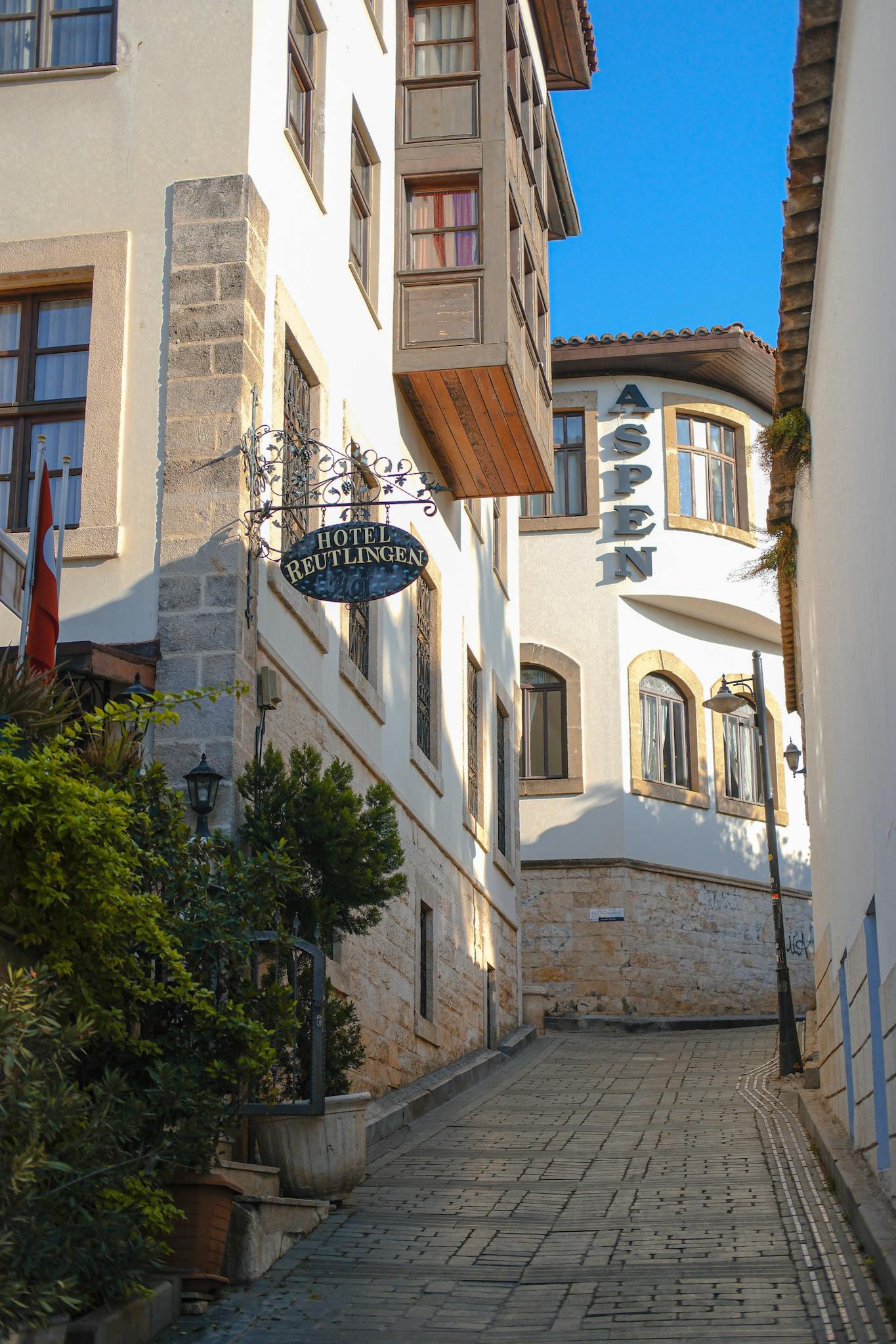 Picturesque alley in Antalya with historic buildings and hotel signs, perfect for travel inspiration.