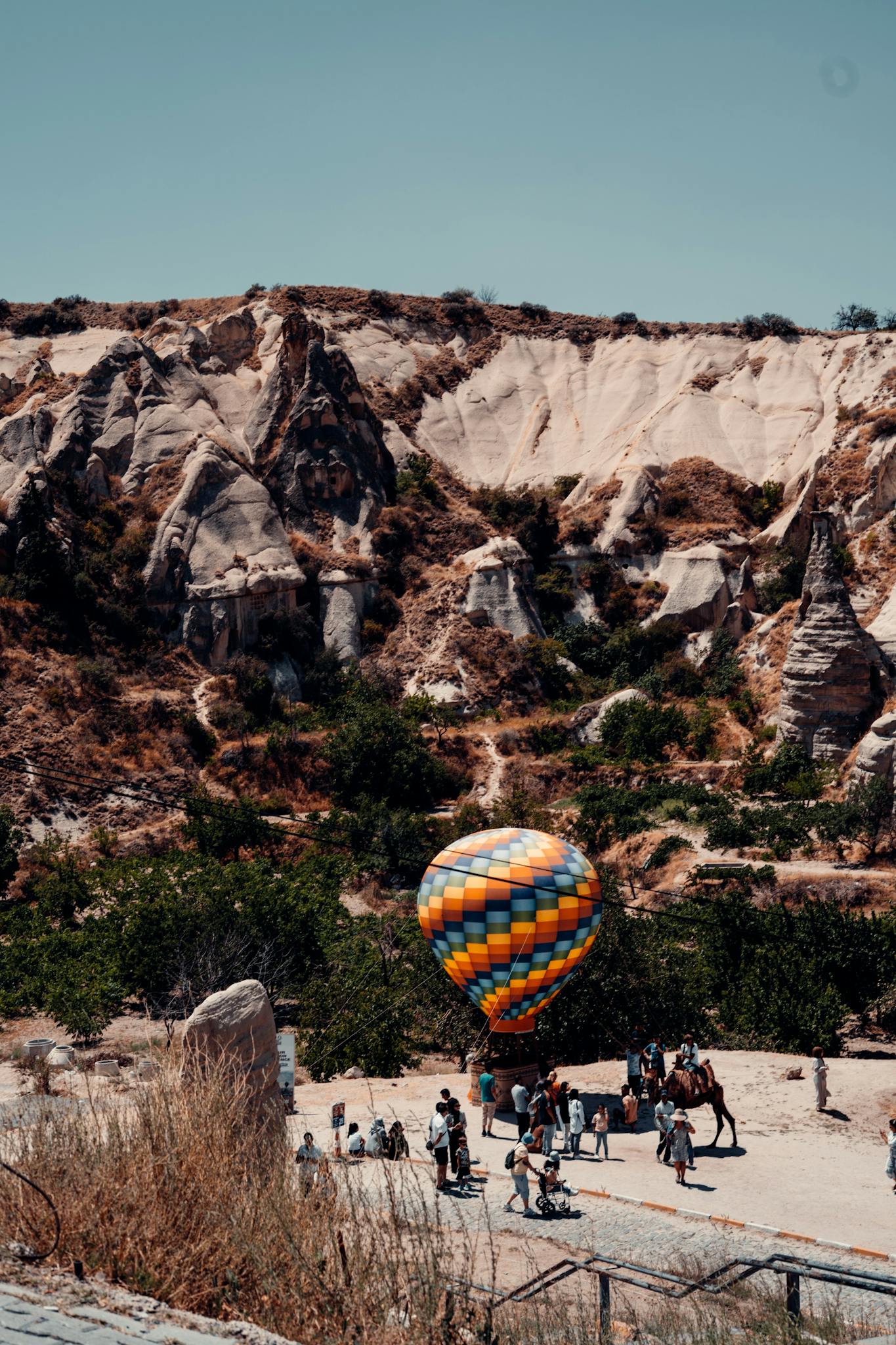 Vibrant hot air balloon at Cappadocia's rocky landscape in Türkiye.